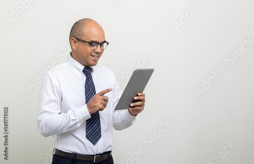 Portrait of Young asian businessman using digital tablet on isolated white background. Handsome middle aged Indian businessman holding tablet computer in office uniform.