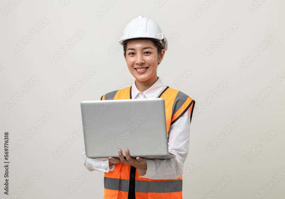 Asian engineer worker woman or architect with white safety helmet standing on isolated white background. Mechanic service factory Professional job occupation in uniform working with laptop computer Asian engineer worker woman or architect with white safety helmet standing on isolated white background. Mechanic service factory Professional job occupation in uniform working with laptop computer