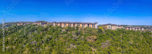 Apartment complex on a mountain top with green trees against the blue sky in Austin, Texas. Panorama of a multi-storey apartment buildings.