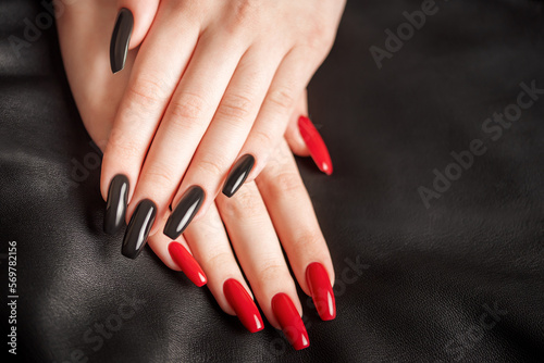 Hands of a young girl with black and red manicure on nails