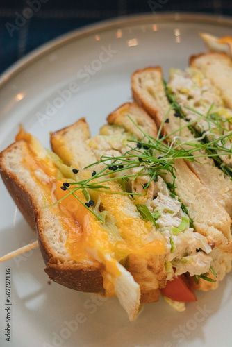 sandwich with egg cheese and herbs cut on a plate close-up