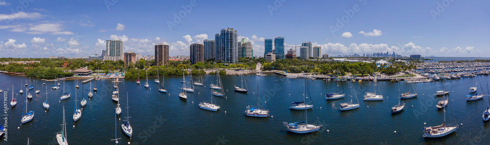 Dinner Key Marina and Coconut Grove Sailing Club with Miami Florida skyline. Panorama of ocean with waterfront buildings and lush green foliage in the background.