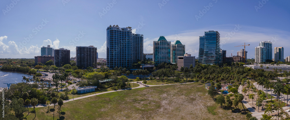 Panorama of beautiful Miami Florida city skyline on a bright sunny day. Modern buildings, partial view of ocean, and wide green lawn can be seen in this scenic landscape.