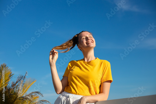Happy joyful positive girl, young beautiful feeling carefree woman is enjoying vacation at summer sunny day, sunbathing, tanning and smiling. Happiness, freedom concept on sky natural background