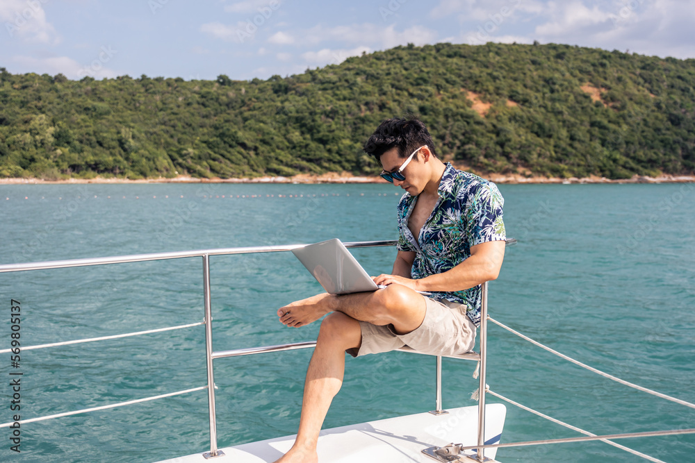 Asian young handsome businessman use laptop computer working in yacht. 