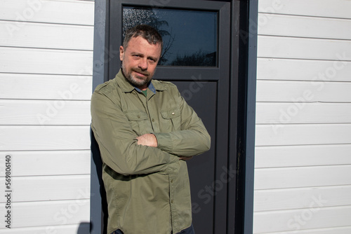 Handsome fifties middle aged man front white wooden home hut