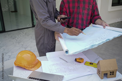 Smiling young architect or engineering builder in hard hat with tablet over group of builders at construction site, architect watching some a construction, business, building, industry, people concept