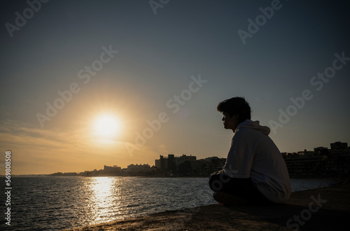 Asian boy looking at view on seaside during sunset