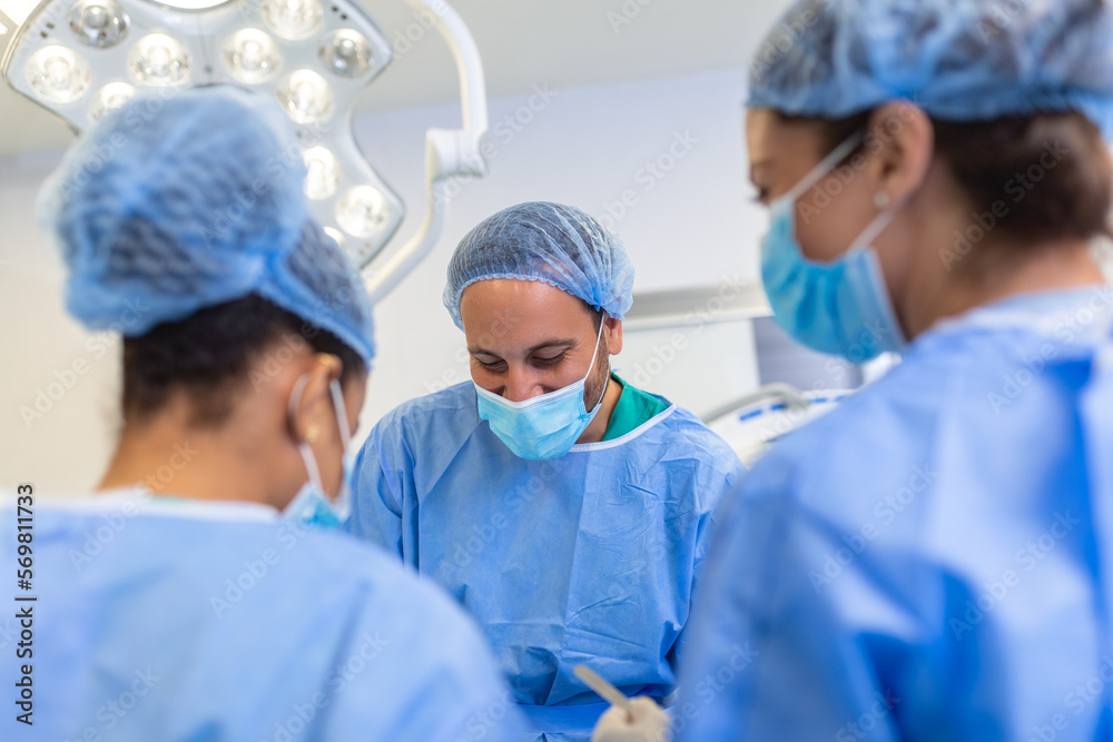 Group of medical team urgently doing surgical operation and helping patient in theater at hospital. Medical team performing surgical operation in a bright modern operating room Group of medical team urgently doing surgical operation and helping patient in theater at hospital. Medical team performing surgical operation in a bright modern operating room