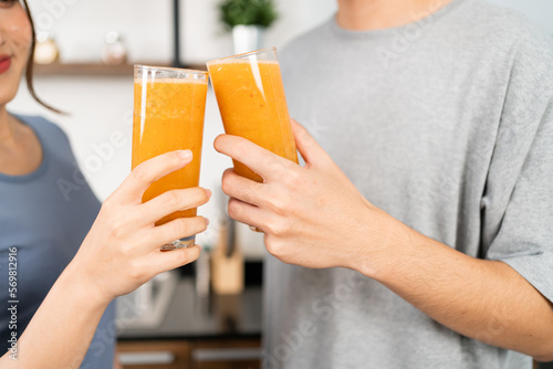 Crop image of happy Asian couple enjoy drinking healthy vegan smoothie in the kitchen counter. Couple making vegan smoothie together at home for a healthy lifestyle.