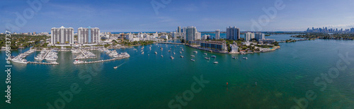 Panoramic view of intracoastal waterway in between modern high-rise buildings - Miami Beach, Florida. Waterfront houses with boats on the blue waterway and a blue sky background. © Jason