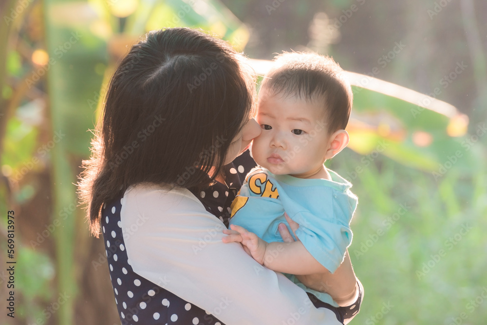 Fototapeta premium Soft focus portrait of happy loving mother and her baby outdoors,Beautiful young mother holds a baby