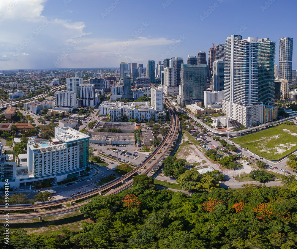 Fototapeta premium Aerial view of Miami Florida with buildings roads and trees on a sunny day. Beautiful urban landscape with condominiums and skyscrapers on the city skyline against blue sky.