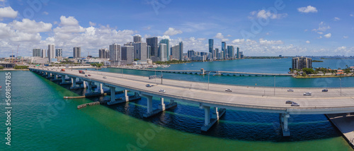 Florida State Road A1A and Intracoastal Waterway in Miami Florida on a sunny day. Scenic city skyline with road and buildings amid inland water channel against clouds and blue sky.