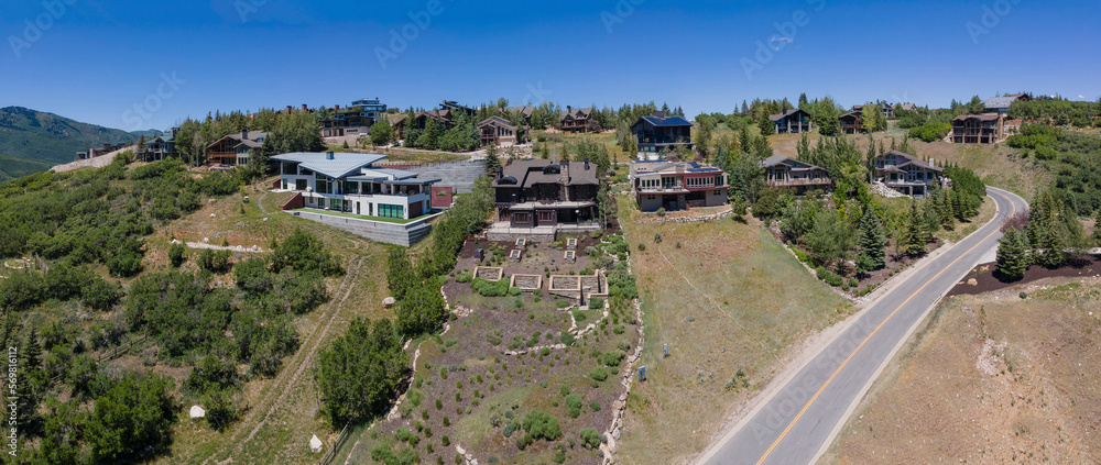 Exterior of multi storey homes in the mountains of Park City Utah on a sunny day. Aerial view of a beautiful residential neighborhood with houses against nature scenery and blue sky.