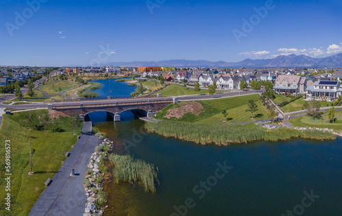 Bridge over river against houses and mountains in Daybreak Utah. Panoramic view of a peaceful residential neighborhood with beautiful nature scenery.
