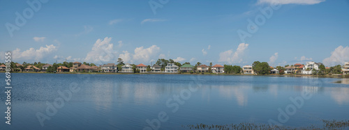 Four Prong Lakefront of single-family homes at Destin, Florida panorama. There is a clean blue reflective lake water at the front of the residences and a background with puffy clouds in blue sky.