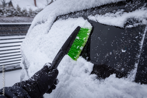 Clearing snow from car windows during a winter snowstorm