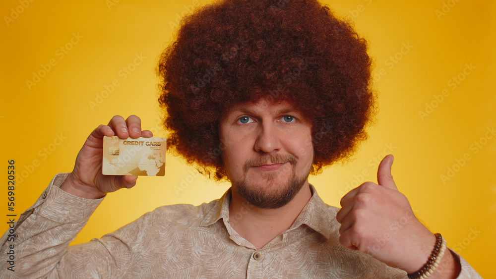 Φωτογραφία Man with afro hairstyle showing plastic credit bank card advertising transferring money cashless, purchases online shopping, sale discount, internet order delivery purchase