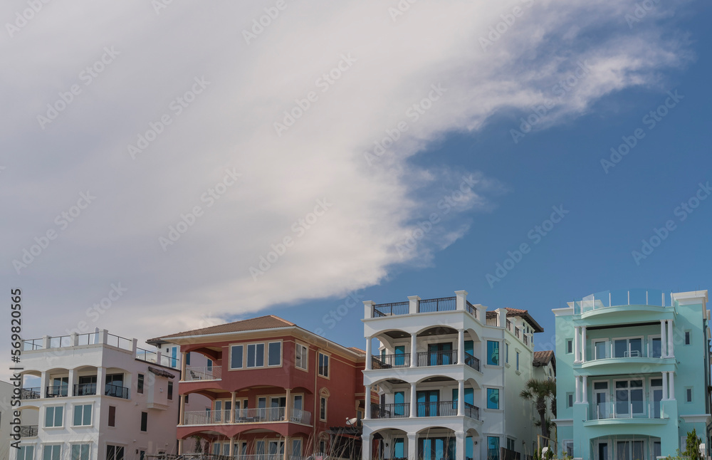 Row of colorful houses with balconies and roof decks against the giant clouds in Destin, Florida. Front exterior of multi-storey beach houses.