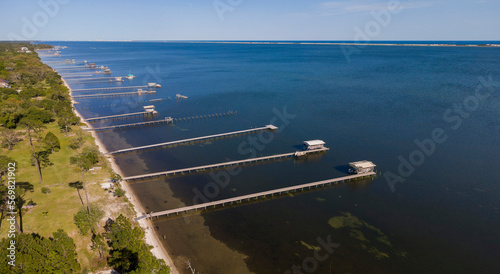 Aerial view of private docks on a vast blue waterfront at Navarre, Florida. Private docks with roofs and long walkway to the boats.