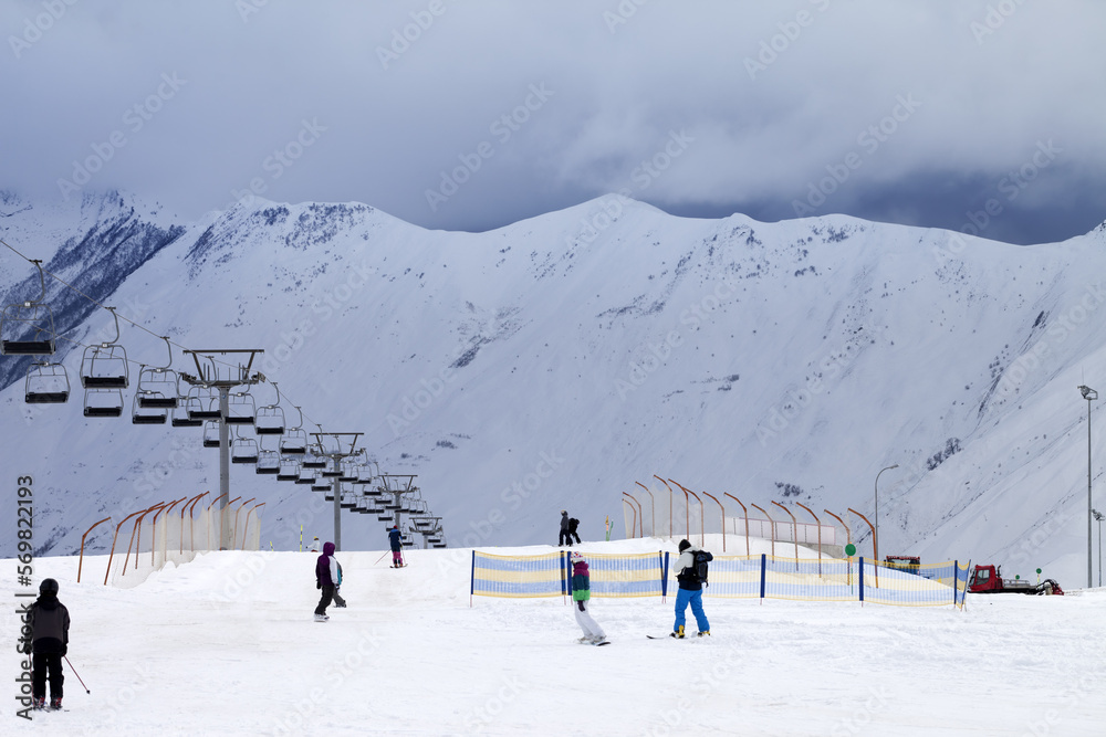 Ski slope with skiers and snowboarders in evening