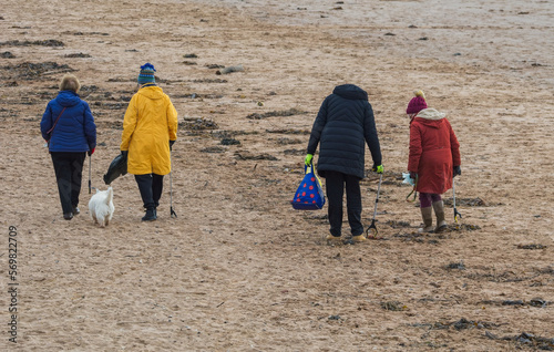 Environmentally aware elderly group of women litter pick on the beach. Collecting rubbish washed up along the sand. Community recycling and keeping our beaches clean. photo