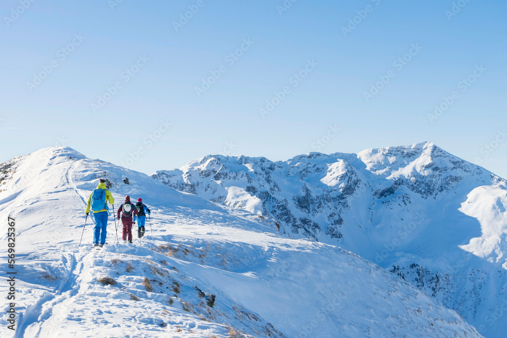 Rear view of skiers climbing on snow mountain Rear view of skiers climbing on snow mountain