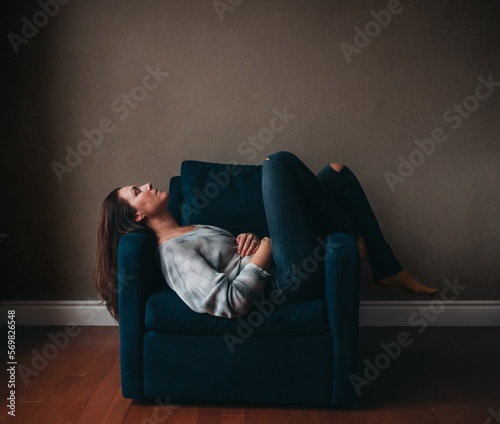 Attractive woman resting in a comfortable chair in an empty room.