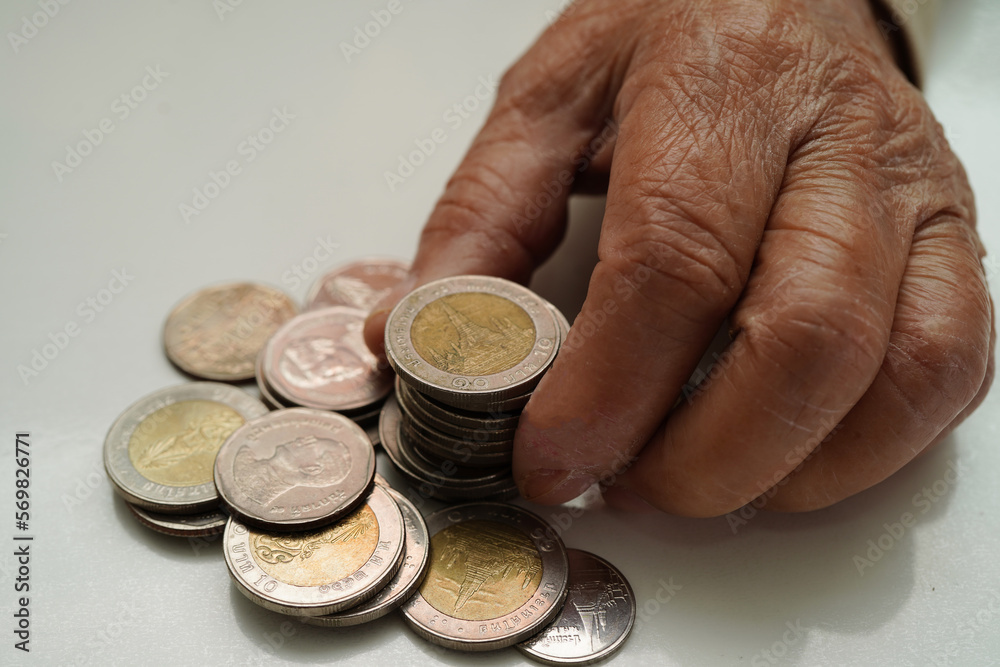 Fototapeta premium Retired elderly woman counting coins money and worry about monthly expenses and treatment fee payment.