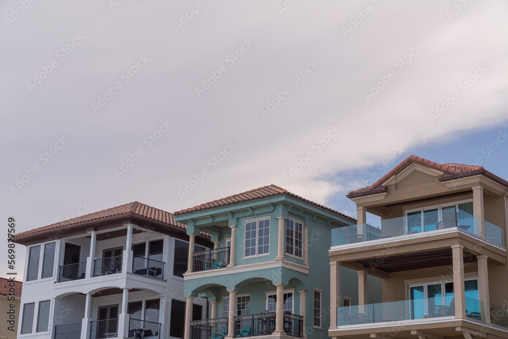 Low angle view of beach houses with balconies against the white giant clouds at Destin, Florida. Three modern beach houses architecture with balconies.