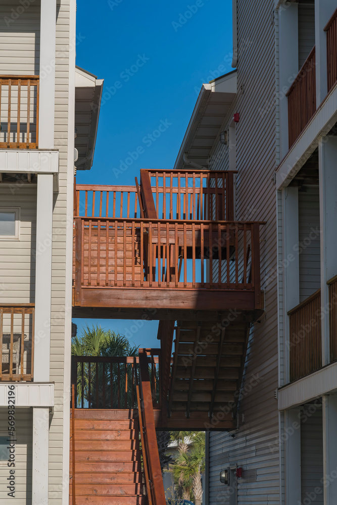 Wooden stairs in outside connecting the two residentia; buildings at Destin, Florida. Stairs in between the building with balconies and white wood sidings.