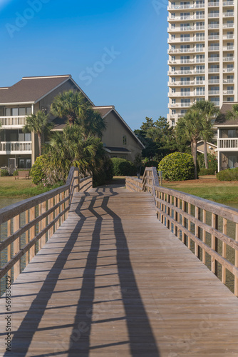 Wooden boardwalk with an arched bridge heading to the apartments in Destin  Florida. Pathway over the lake at the front of residential area.