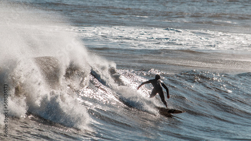 Photography An athlete or sportsman surfing an awesome blue wave in autumn in Europe