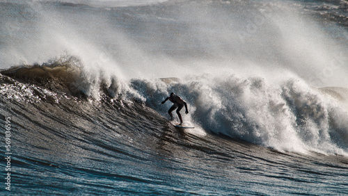 A brave surfer doing tricks in a massive wave from a big storm at winter photo