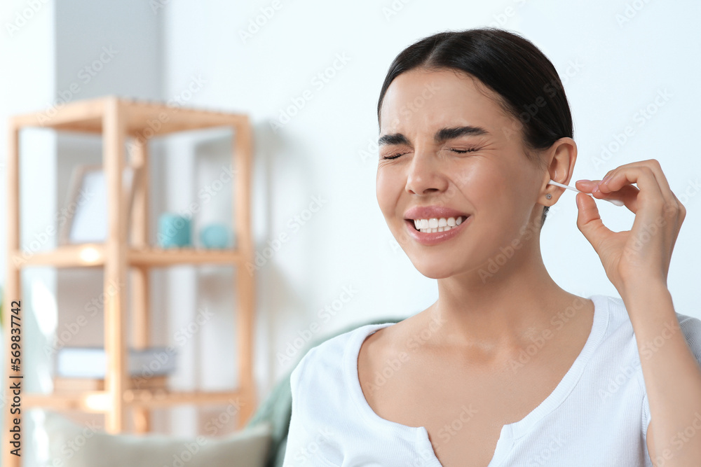 Young woman cleaning ear with cotton swab at home Young woman cleaning ear with cotton swab at home