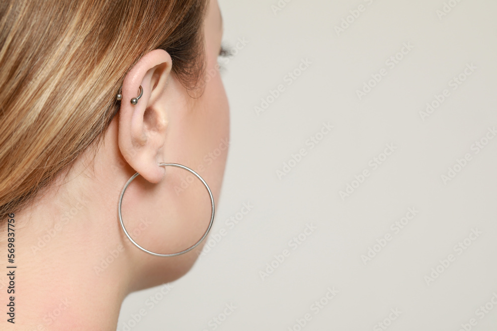 Young woman with ear piercing on white background, closeup. Space for text Young woman with ear piercing on white background, closeup. Space for text