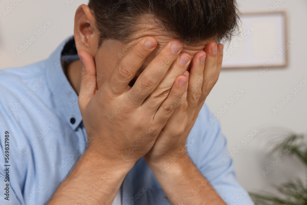 Sad man closing his face with hands indoors, closeup Sad man closing his face with hands indoors, closeup