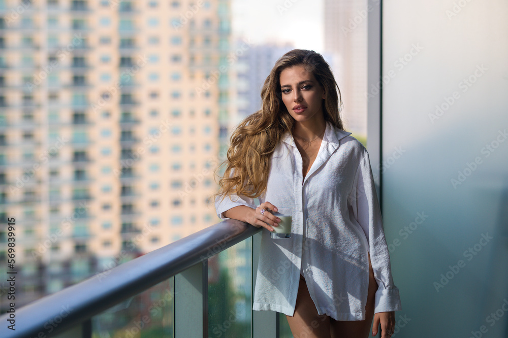 Fototapeta premium Morning healthy breakfast. Young woman with glass of milk on balcony terrace. Girl drinking milk at home. Beautiful woman holding milk glass. Lactose free milk, concept. Morning beverage.