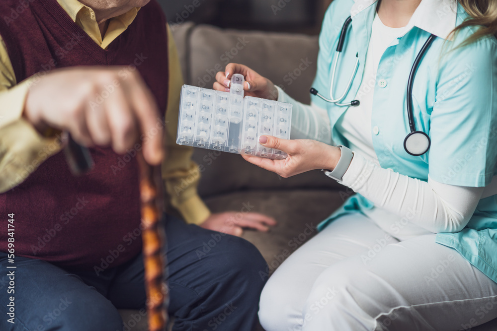 Nurse home caregiver is assisting old man at his home. Professional health support for elderly people.