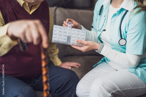 Nurse home caregiver is assisting old man at his home. Professional health support for elderly people.