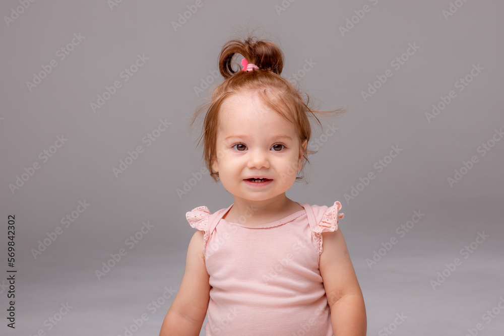 healthy baby girl in a pink bodysuit sits on a white background. space for text healthy baby girl in a pink bodysuit sits on a white background. space for text