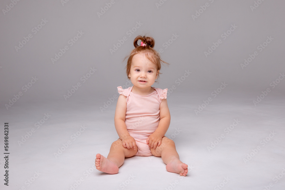 healthy baby girl in a pink bodysuit sits on a white background. space for text healthy baby girl in a pink bodysuit sits on a white background. space for text