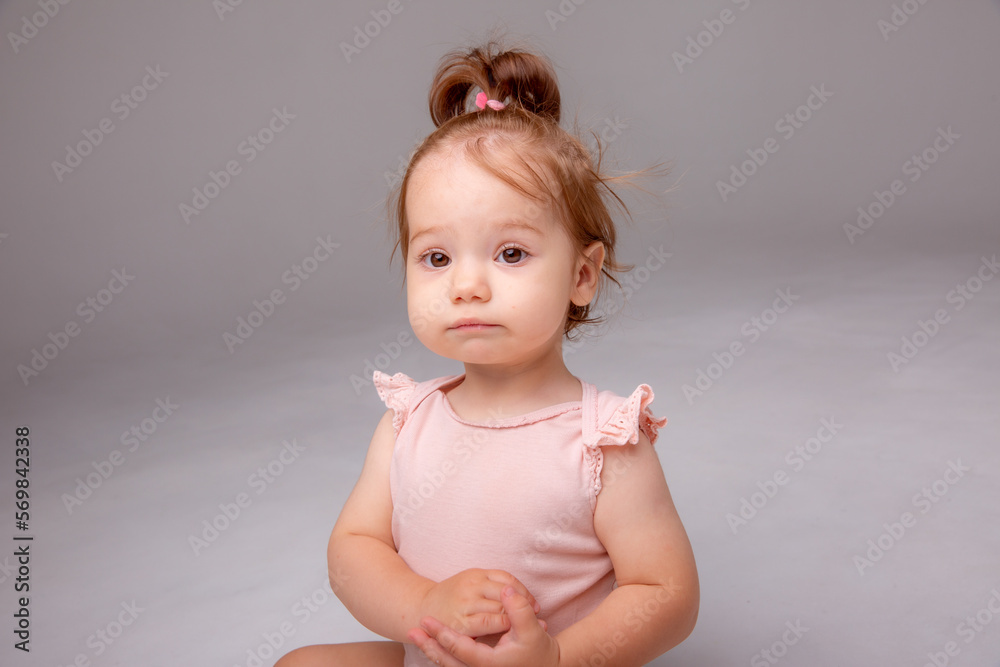 healthy baby girl in a pink bodysuit sits on a white background. space for text healthy baby girl in a pink bodysuit sits on a white background. space for text