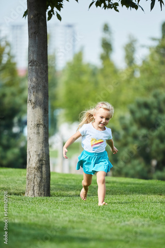 A little girl runs through the grass in the park. The concept of childhood
