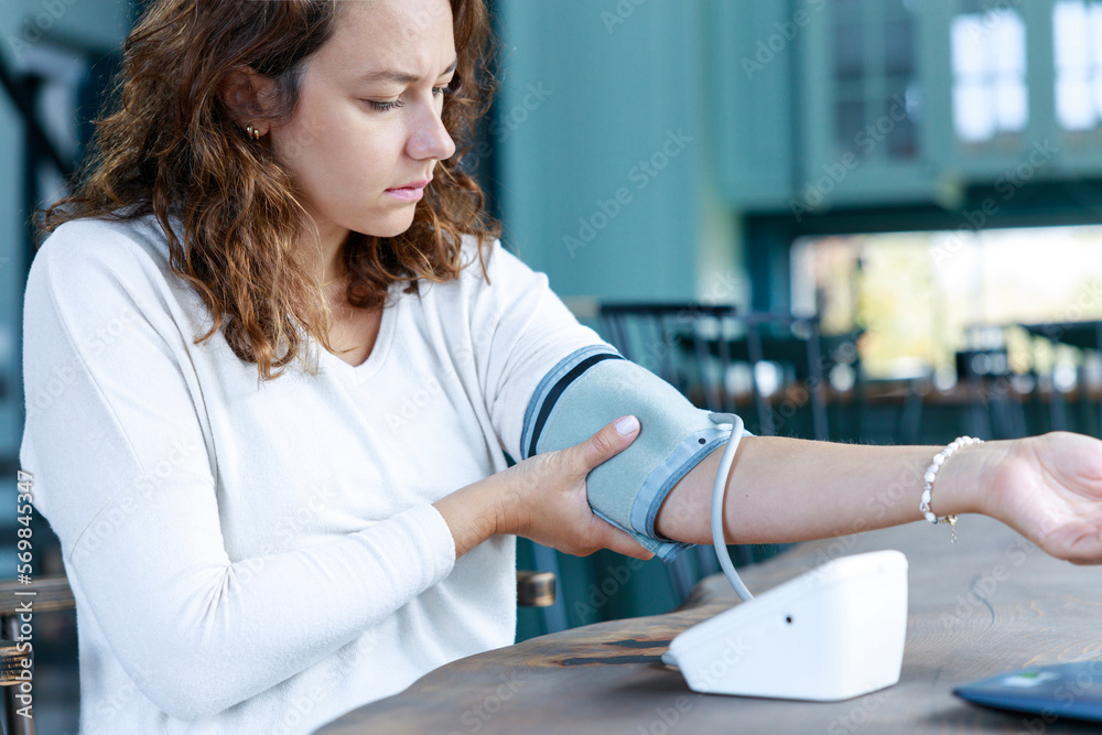 Young freelancer woman checking blood pressure at her desk Young freelancer woman checking blood pressure at her desk