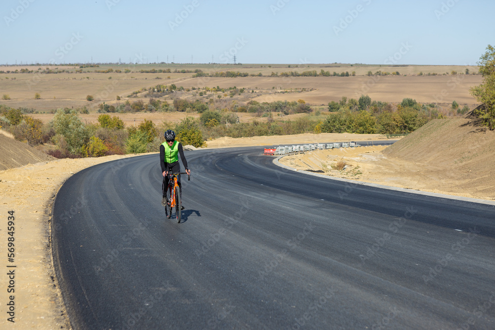 Cyclist riding bicycle on road against clear sky Cyclist riding bicycle on road against clear sky