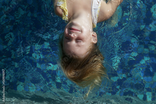 Portrait of adorable 5 years old girl floating in the swimming pool