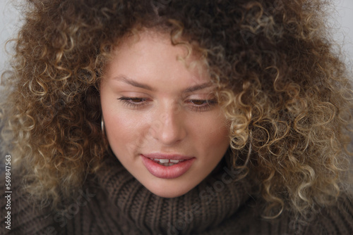 Portrait of beautiful curly woman working on computer. Young adult female person with curls reading text on laptop screen in close up