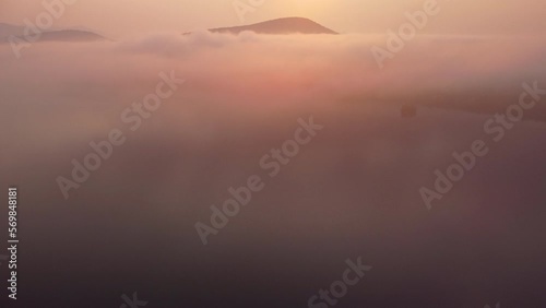A Sunrise drone video over fog with mountains in the background